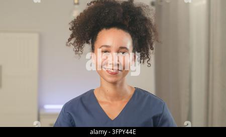 Nurse poses for a healthcare portrait in blue scrubs at a clinic Stock Photo