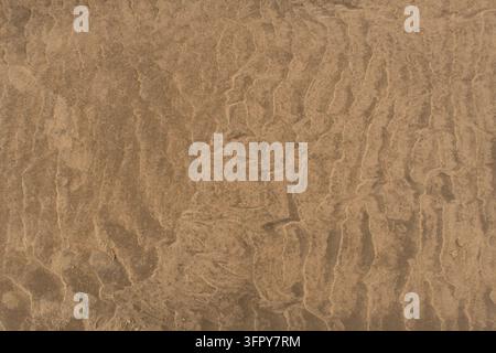 Wet sand texture with natural tidal patterns and soft coastal background Stock Photo