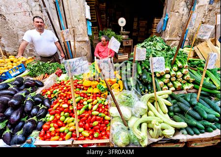 Two vendors with eggplants, tomatoes, peppers, zucchini and handwritten euro price signs at an outdoor food market in Sicily, Italy. Stock Photo