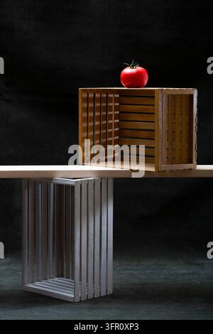 Two empty wooden crates against a dark green background and a red tomato Stock Photo