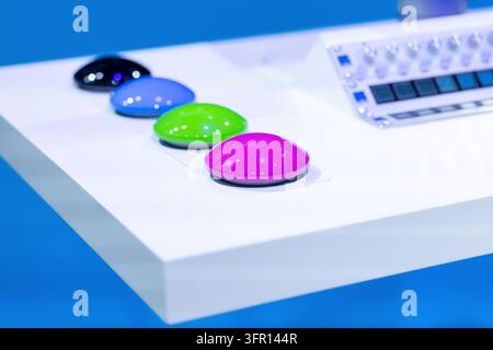 Four colorful glossy computer mice rest in a row on a white display table, with a keyboard partially visible behind them in a modern showroom Stock Photo