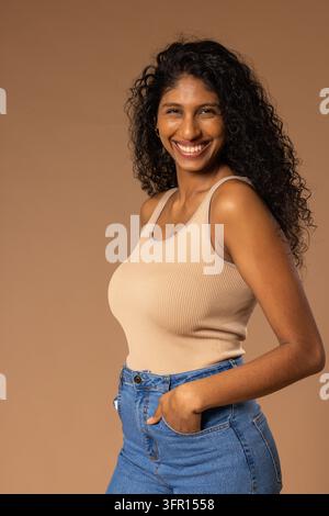 African American woman posing in studio three-quarter turn, smiling and wearing tank top and jeans Stock Photo