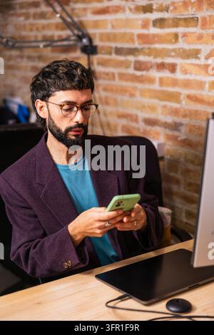 Focused art director using smartphone in creative office Stock Photo