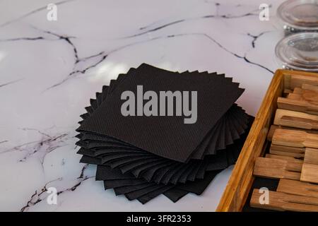 Fanned stack of black paper napkins on white marble background Stock Photo