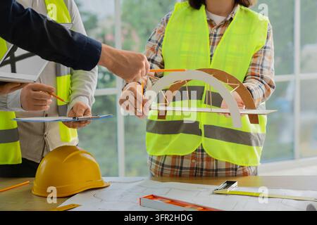 Team collaboration and engineering project, architects and civil engineers discussing bridge model and construction blueprints in office Stock Photo