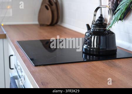 Close up view of modern black electric glass stove embedded in wooden kitchen countertop, home design, cozy lifestyle. Stock Photo