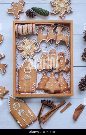 Assorted Christmas themed cookies and biscuits on wooden tray with white wooden background and cinnamons. Stock Photo