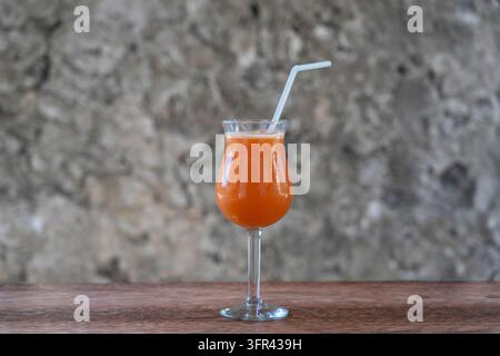 Freshly squeezed juice from tropical fruits in a glass goblet on the background of an old stone wall. Island of Zanzibar, Tanzania, East Africa. Close Stock Photo
