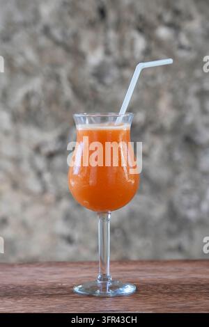 Freshly squeezed juice from tropical fruits in a glass goblet on the background of an old stone wall. Island of Zanzibar, Tanzania, East Africa. Close Stock Photo