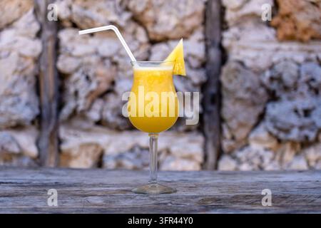 Freshly squeezed juice from pineapple in a glass goblet on the background of an old stone wall. Island of Zanzibar, Tanzania, East Africa. Close up, c Stock Photo