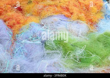 Close view of tangled fishing nets in bright orange, green, blue, purple and white tones. Stock Photo