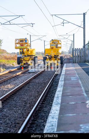 Specialized heavy yellow machinery for track repair and overhead line maintenance sits idle on the railway line operating on the East Coast Mainline. Stock Photo