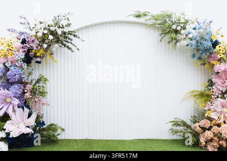 White arched wedding backdrop decorated with colorful floral arrangements on both sides Stock Photo