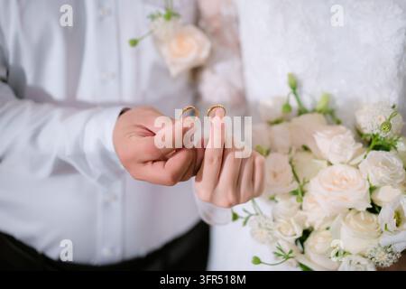 Bride and groom holding up matching gold wedding bands during a ceremony Stock Photo