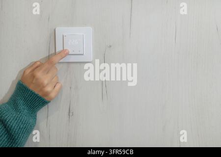 Hand Pressing White Light Switch on Wall with Copy Space  Stock Photo