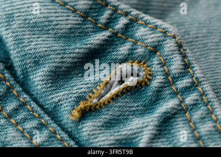 Worn blue denim fabric showing detailed texture, yellow stitching, and a well-defined buttonhole, highlighting garment craftsmanship Stock Photo