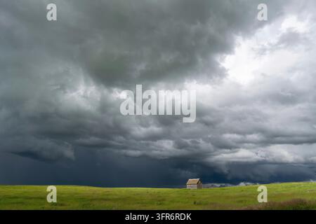 Ominous supercell storm clouds gathering over a lonely abandoned barn in the vast great plains Stock Photo