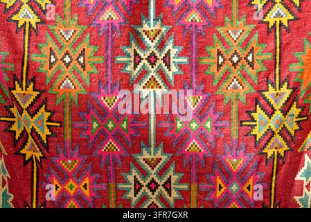 Traditional handwoven Tunisian kilim carpet, photographed on 10.10.2024. The textile features complex geometric tribal patterns in vibrant red, pink, Stock Photo