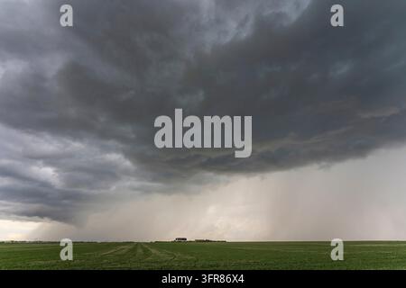 Dramatic storm clouds forming over a green field, creating an ominous atmosphere Stock Photo