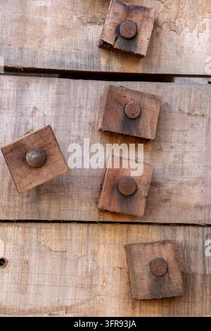Wooden dowels with rusty nail heads are set into the weathered planks of a ship hull in close up, Gujarat, Mandvi, India Stock Photo