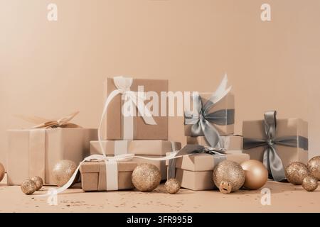 Brown gift boxes, ribbons and gold baubles arranged around beige empty space. Stock Photo