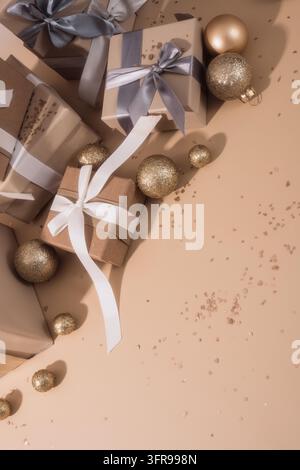 Brown gift boxes, ribbons and gold baubles arranged around beige empty space. Stock Photo