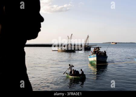 Silhouette of a face in profile looking at the harbour where men row a ...