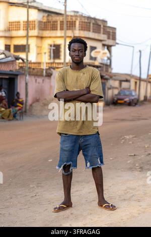 Portrait of a young man standing with arms crossed on a street, Maritime Region, Lome, Togo Stock Photo