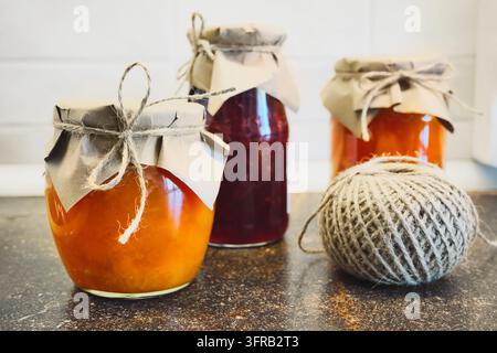 Glass jars filled with homemade fruit preserves and ball of twine ready for crafting Stock Photo