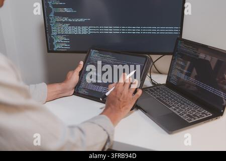 Software engineer using a stylus with a tablet to review source code in a modern workspace. Close-up of programming, code debugging, software developm Stock Photo