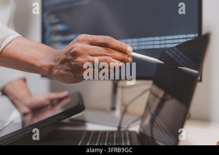 Software engineer using a stylus with a tablet to review source code in a modern workspace. Close-up of programming, code debugging, software developm Stock Photo
