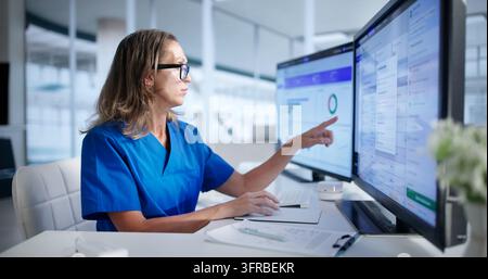 Healthcare Manager Carefully Reviews Medical Claims On Computer Screen. Stock Photo