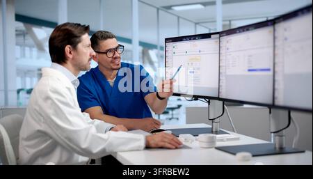 Healthcare Manager Carefully Reviews Medical Billing Software For Optimizing Revenue Cycle. Stock Photo