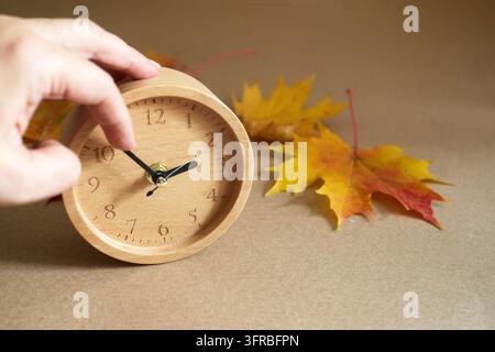 Hand adjusting wooden clock for daylight saving time change Stock Photo