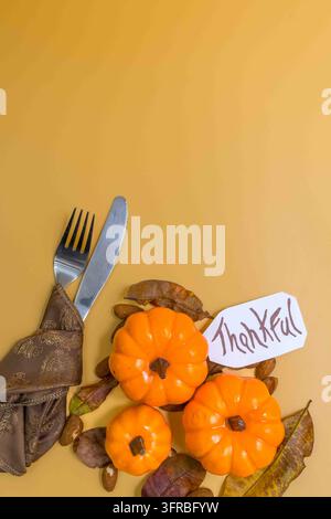 Dining table setting featuring mini pumpkins, dry leaves, and a thankful tag Stock Photo