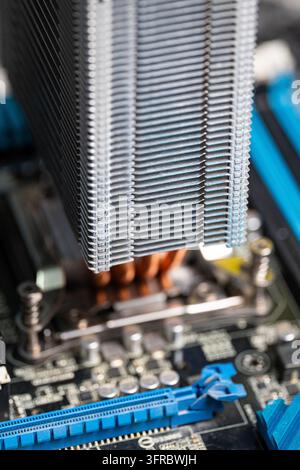 Close-up of a metal CPU cooling tower with copper heat pipes mounted on a computer motherboard processor socket, showcasing internal PC hardware and c Stock Photo