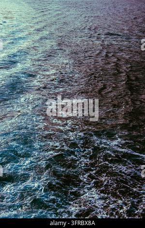 Close-up of blue ocean water with intricate ripples, flowing currents, and shimmering reflections in turquoise and deep violet tones. A dynamic aquati Stock Photo