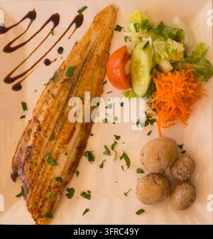 Fried plaice with canarian potatoes and vegetable salad on a plate Stock Photo