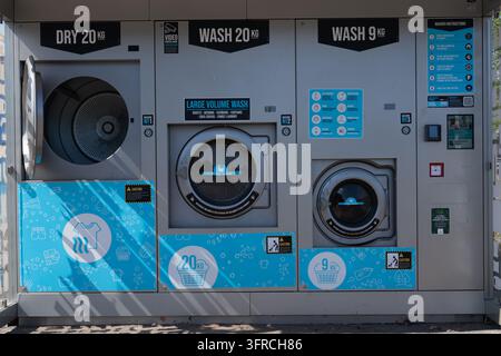 An automated outdoor self-service laundry station with washing and drying machines installed in a public area, offering quick and convenient clothes w Stock Photo