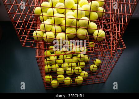 Tennis balls in stacked wire hoppers close up representing a sports training, tennis academy education, and active lifestyle concept. Horizontal high- Stock Photo