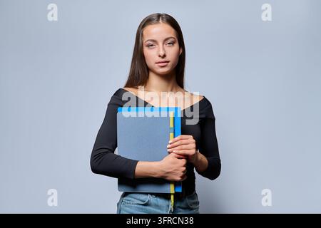 Young female student holding notebook in studio portrait Stock Photo