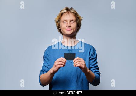 Smiling student holding black transit pass looking at camera in studio Stock Photo