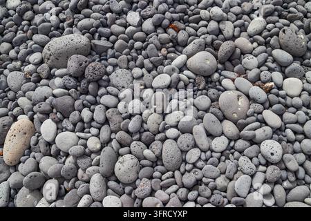 Natural background of smooth grey and black volcanic pebbles on a beach Stock Photo