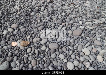 Natural background of smooth grey and black volcanic pebbles on a beach Stock Photo
