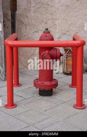Bright red fire hydrant protected by metal safety guard on a paved. High quality photo Stock Photo
