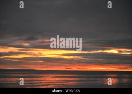 Fiery Orange Sunset Over the Sea Beneath Dark Clouds in Punta Arenas, Chile Stock Photo