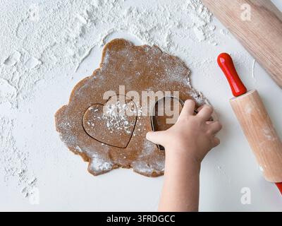 Children making heart shaped cookies with dough and rolling pin Stock Photo
