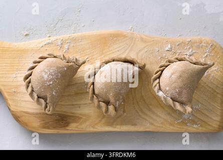 Making pies from rye dough on a wooden board, top view. Cooking stage Stock Photo