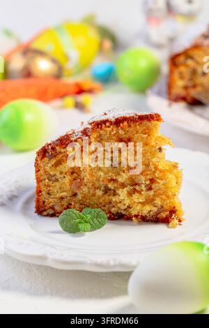 Slice of traditional carrot cake sprinkled with powdered sugar, served on plate with mint. Concept of desserts for the Easter holiday Stock Photo