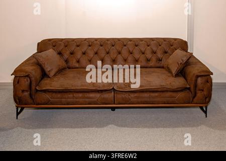 Retro brown leather Chesterfield style sofa furniture in room interior Stock Photo